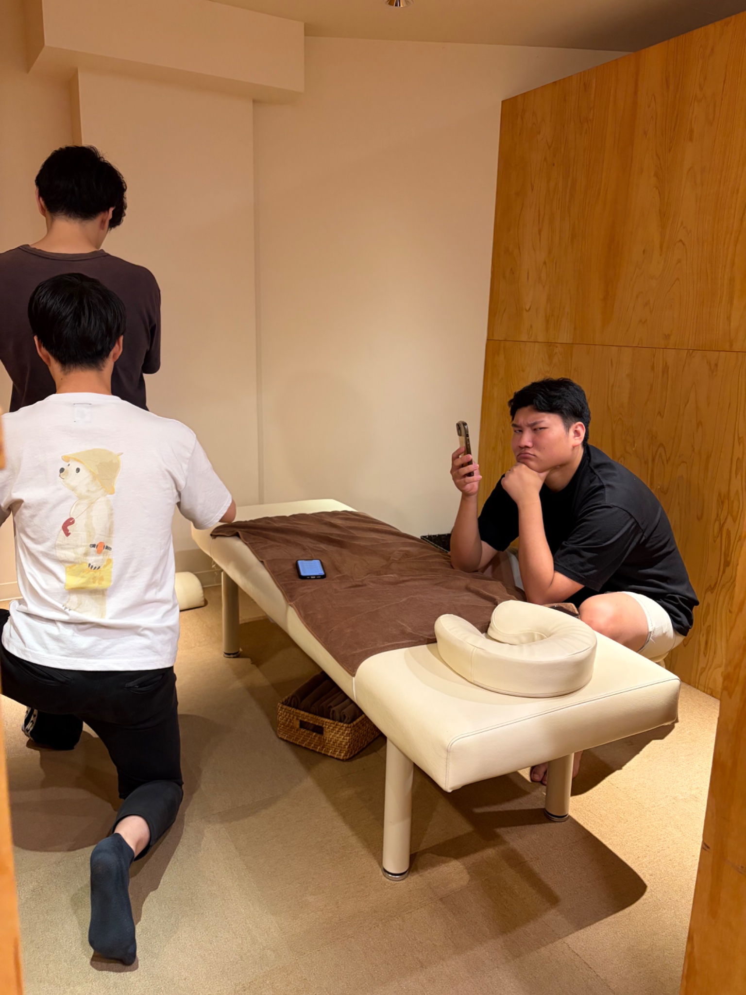 とんとん整骨院の練習会でベッドサイドに集まって確認し合うスタッフ